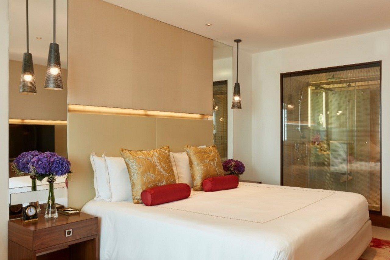 The Taj Mahal Tower, Mumbai Ξενοδοχείο Εξωτερικό φωτογραφία The photo shows a modern bedroom with a stylish design. It features a large bed with white linens and decorative pillows in gold and red. The walls are neutral, and there are pendant lights hanging above the bed. To the side, there is a wooden nights