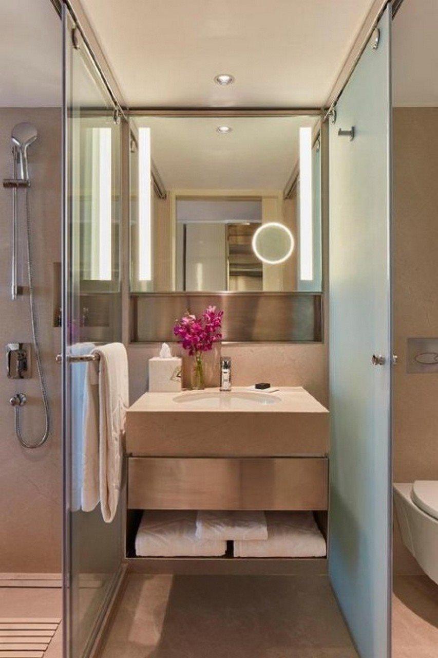 The Taj Mahal Tower, Mumbai Ξενοδοχείο Εξωτερικό φωτογραφία The photo shows a modern bathroom. It features a sleek, minimalistic design with a light-colored sink unit that includes a smooth countertop. On the countertop, there is a vase with purple flowers and a few toiletries. A large mirror with integrated 