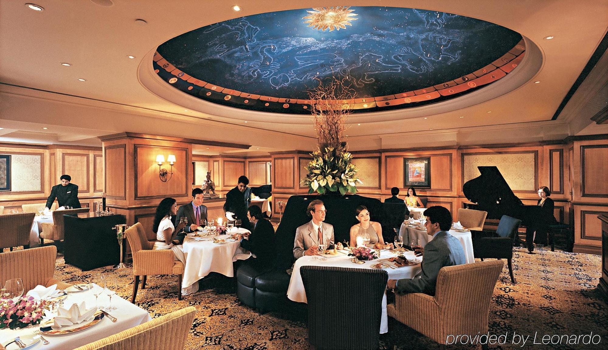 The Taj Mahal Tower, Mumbai Ξενοδοχείο Εξωτερικό φωτογραφία The photo depicts an elegant dining room setting. The ceiling features a beautiful mural of the night sky, complete with stars and a shining sun. There are several tables set for dining, each with white tablecloths, flowers, and fine dining arrangeme