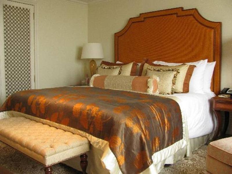 The Taj Mahal Tower, Mumbai Ξενοδοχείο Εξωτερικό φωτογραφία The photo shows a well-decorated bedroom featuring a large bed with an ornate headboard. The bed is dressed with a luxurious comforter that has a blend of rich colors, including brown and gold accents, along with multiple decorative pillows. At the f