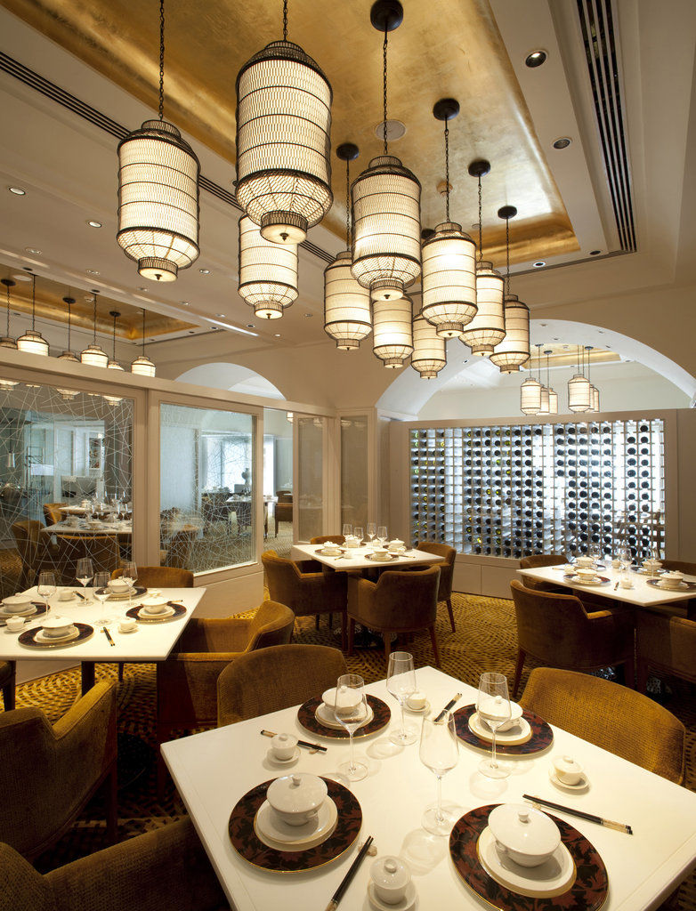 The Taj Mahal Tower, Mumbai Ξενοδοχείο Εξωτερικό φωτογραφία The photo depicts an elegant restaurant interior. It features a sophisticated design with multiple hanging light fixtures that have a distinct, stylish appearance. The tables are round and set for dining, with neatly arranged plates and utensils. The